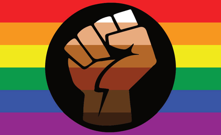 Image of the rainbow-colored background Queer People of Color (QPOC) Pride flag with a raised fist sign representing unity and support as well as defiance and resistance, and the various colors of the fist representing diversity.